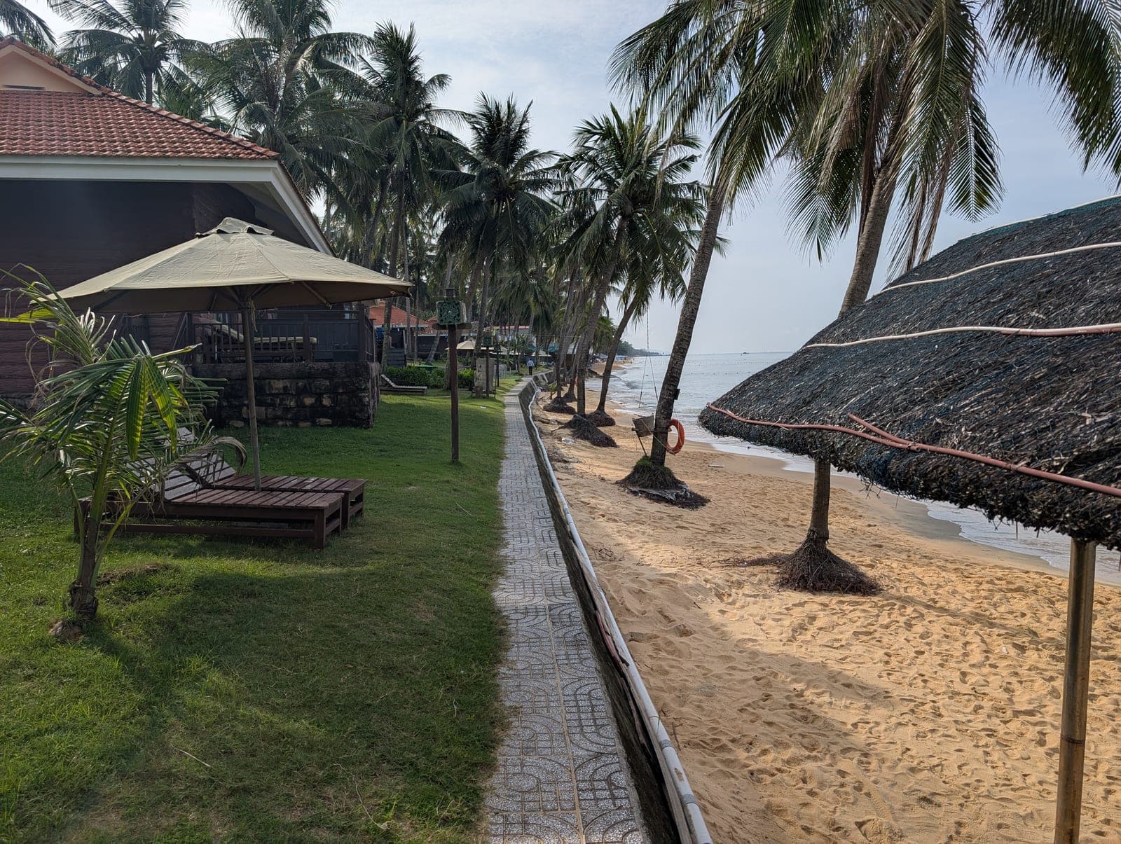 Tropical beach at Phu Quoc Resort and Spa with clear turquoise waters, white sand, and resort facilities along the shoreline.