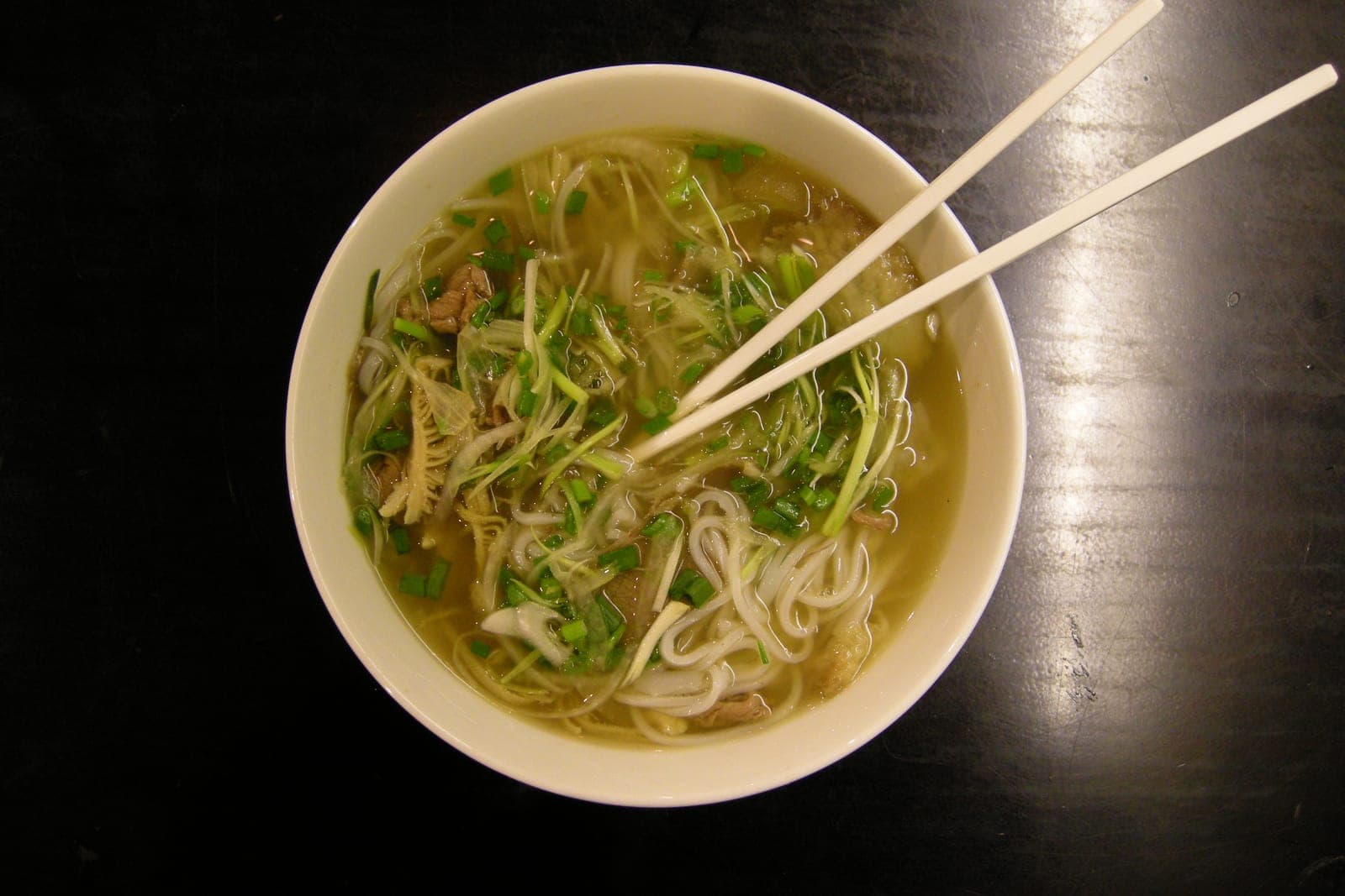 A steaming bowl of pho Vietnamese noodle soup with broth, rice noodles, herbs, and garnishes in Ho Chi Minh City.