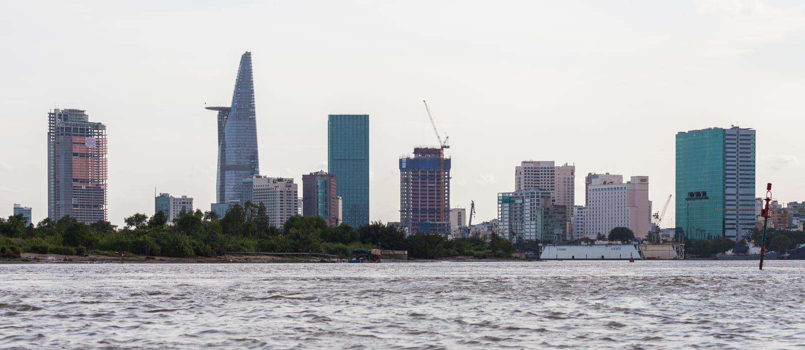 Saigon River flowing through Ho Chi Minh City with urban development and buildings along both banks on a bright day.