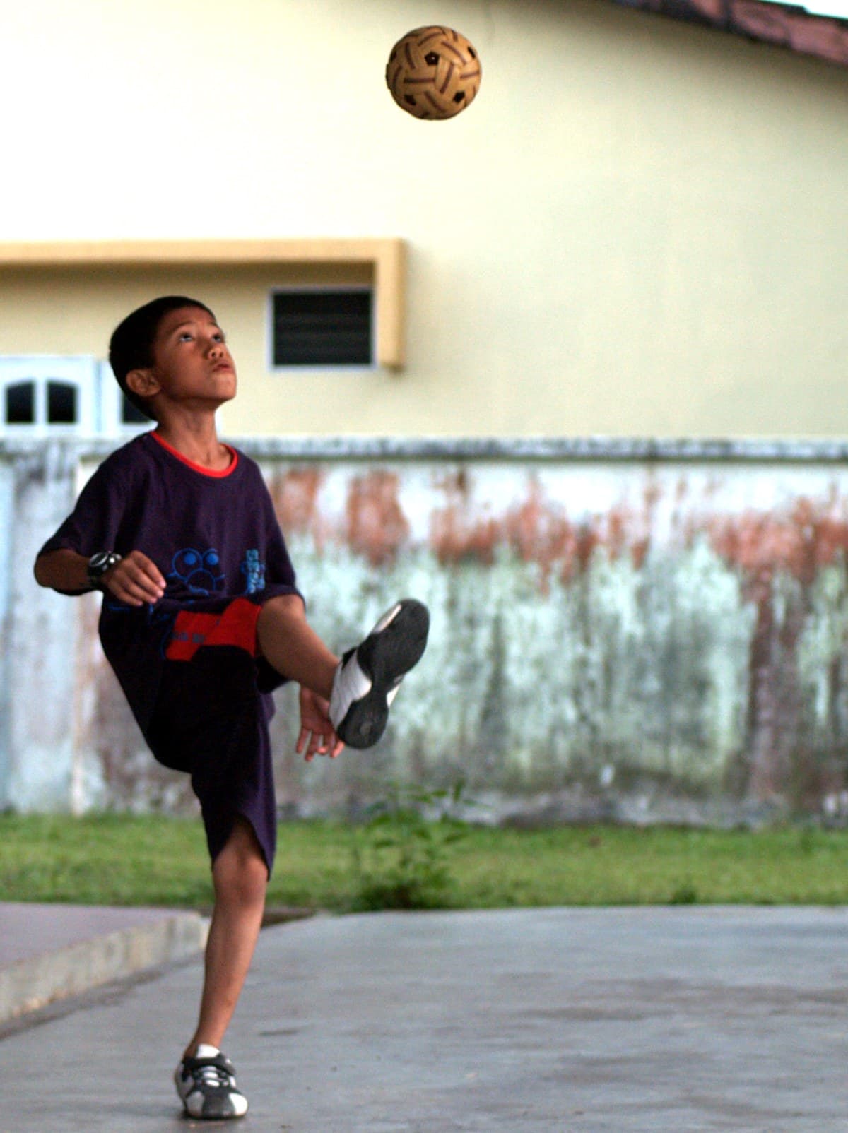 Competitive sepak takraw players executing acrobatic kicks with a light ball over a net during a match.