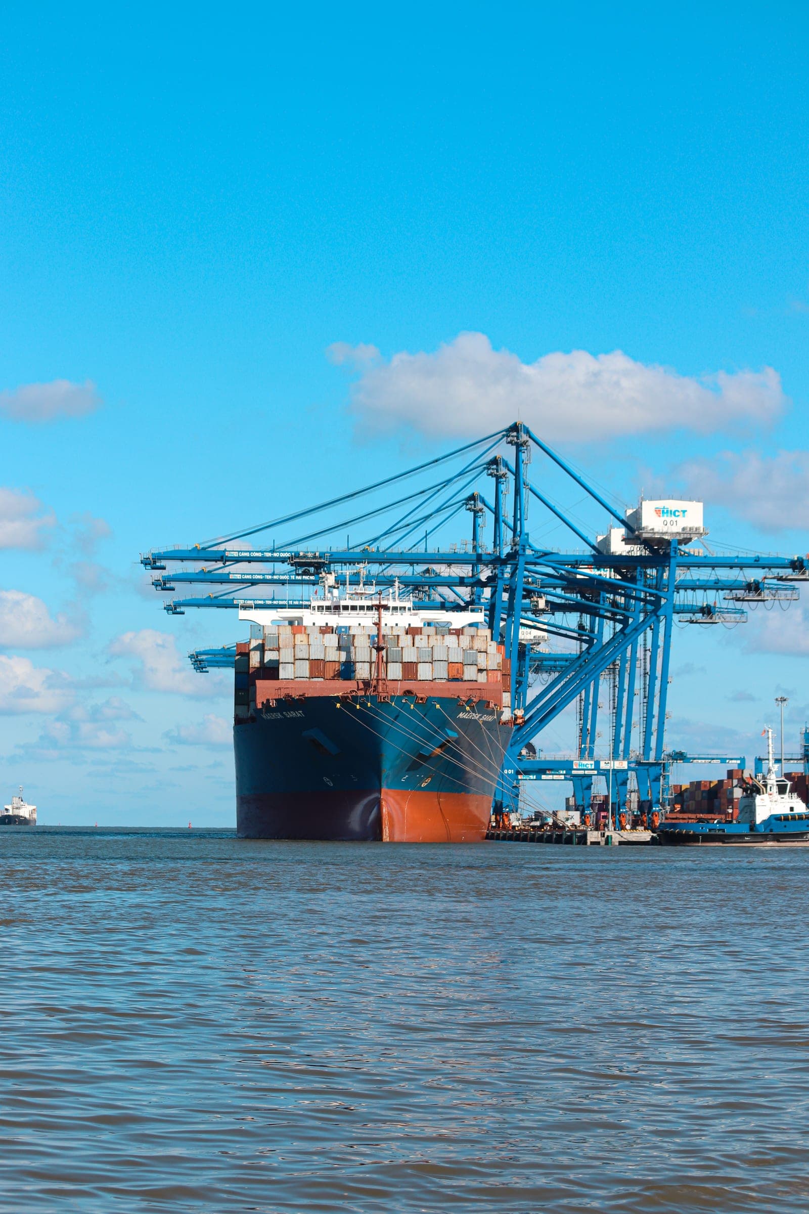 Large container ship docked at Hai Phong International Container Terminal with cargo cranes and stacked shipping containers