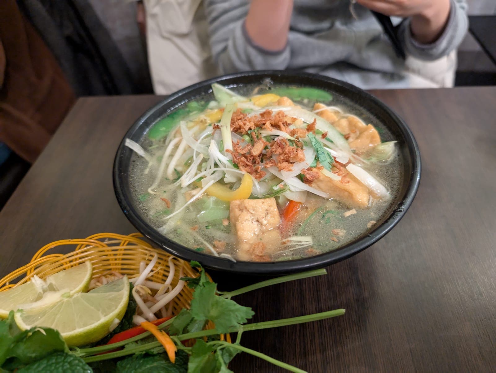 Steaming bowl of tofu phở with noodles and garnishes, showcasing authentic Hanoi-style preparation