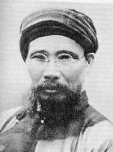Black and white historical portrait photograph of an elderly Vietnamese man with beard, wearing a turban, from early twentieth century.