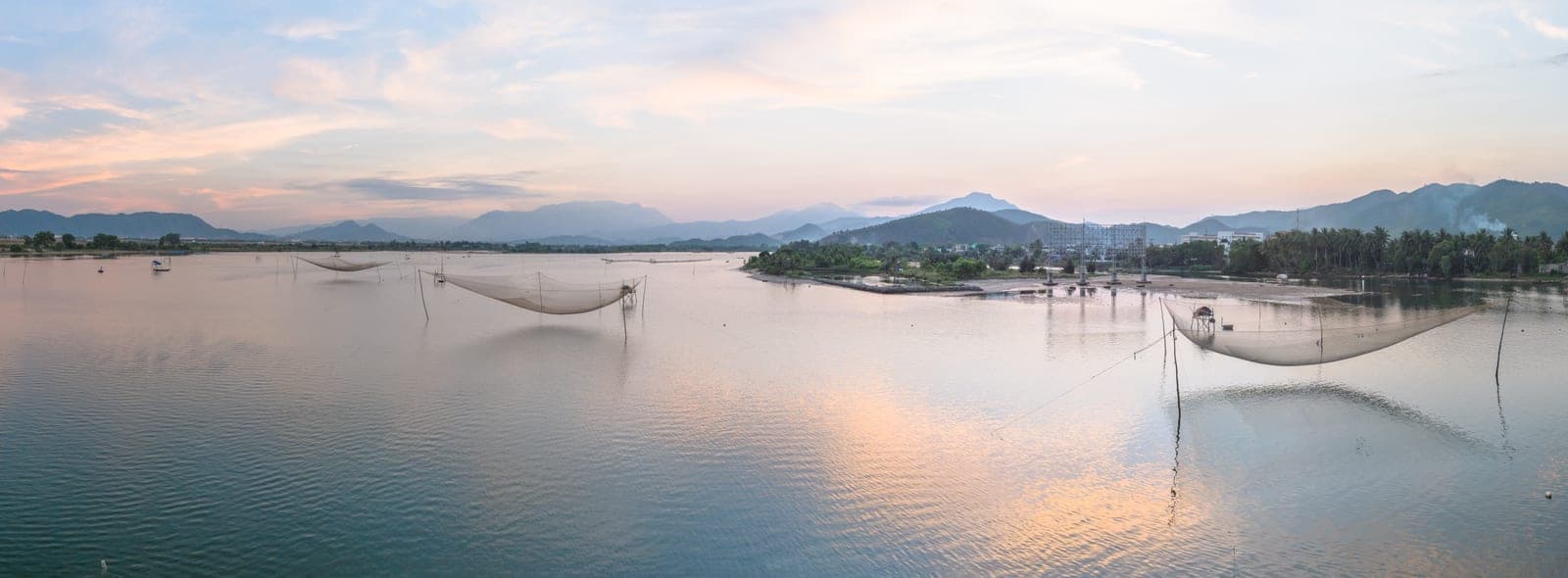 The Cu Đê River flowing through Đà Nẵng with green vegetation along banks and riverside development visible in the distance.
